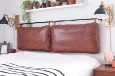 a contemporary meets boho bedroom with a brown leather pillow headboard on a black holder