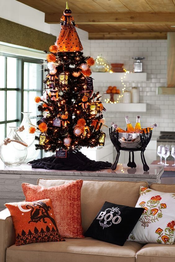 a mini black Halloween tree decorated with white and orange ornaments, lights and a scary pumpkin head doll on top
