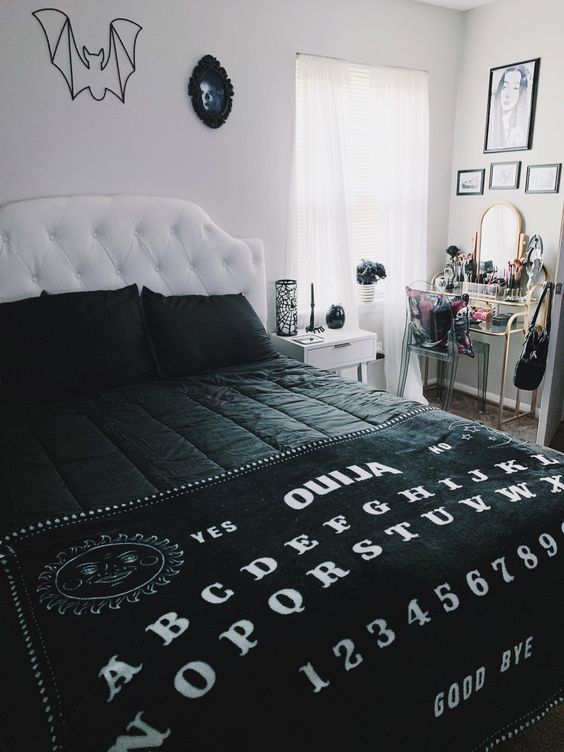 a monochromatic Halloween bedroom with a bat artwork, black bedding, a spiderweb candleholder, a scary photo on the wall