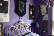 a purple and black bedroom with a bold gallery wall, a forged bed, a black crystal chandelier and a black lamp is gorgeous
