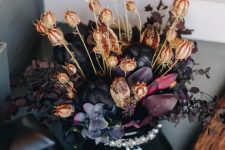 a refined and chic Halloween flower arrangement of deep purple, black blooms and some dried flowers for a decadent feel