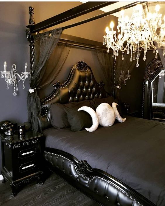 a refined moody bedroom in graphite grey and black, with a statement crystal chandelier, moon phase pillows and candelabra-inspired lamps