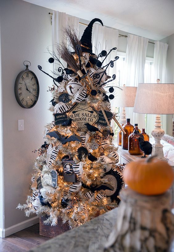 a silver Halloween tree decorated with a witch hat and brooms, with banners, garlands, bats and skulls