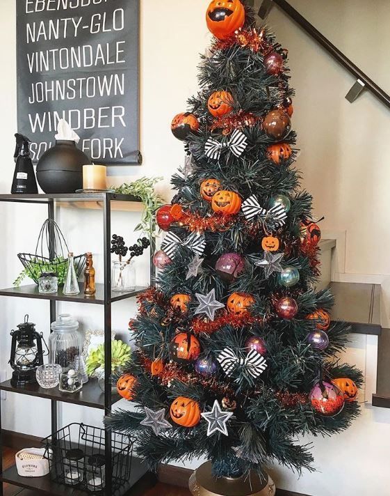 a stylish Halloween tree decorated with bows, colored ornaments, garlands and pumpkin ornaments