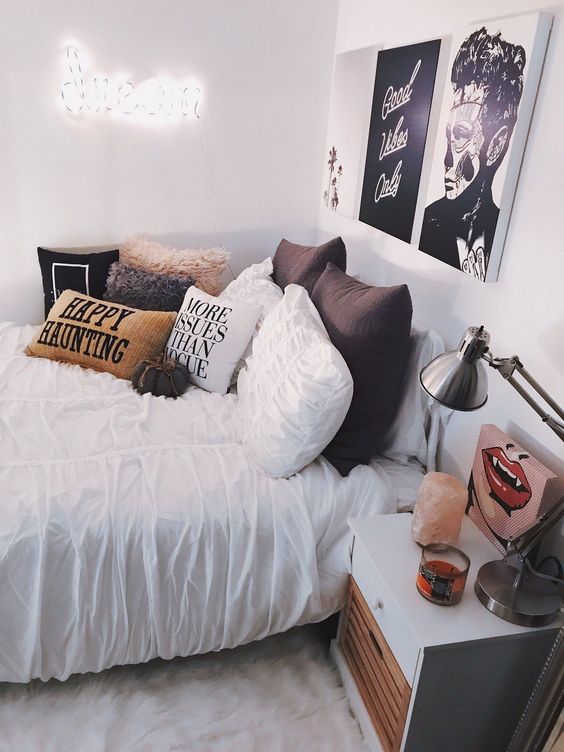 a stylish modern Halloween bedroom decorated with a bold gallery wall, an arrangement of pillows and a small fabric pumpkin