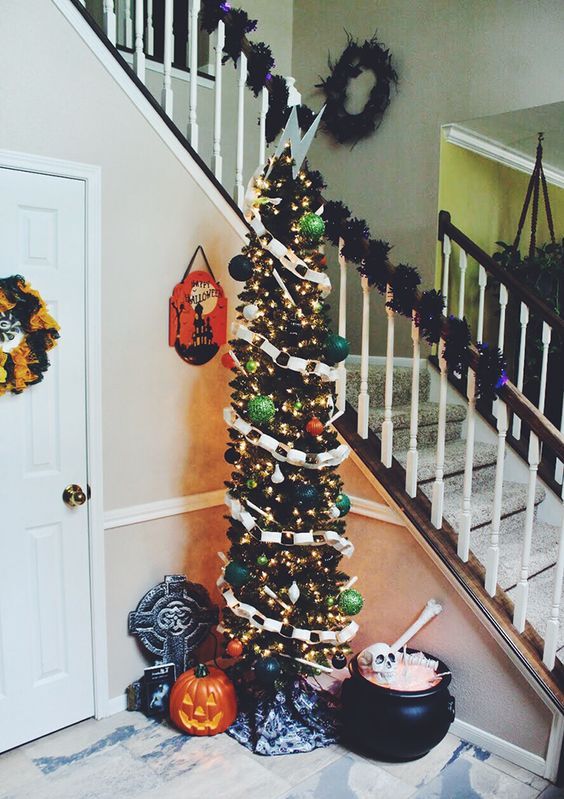 a tall Halloween tree in black decorated with banners, ornaments, lights and topped with a lightning