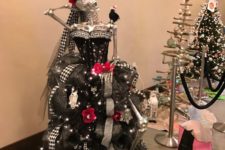 a unique Halloween tree of a silver skeleton, a black strapless dress, lights, banners, garlands and bats