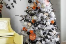 a white Halloween tree decorated with black and orange oranments, banners and garlands and skulls