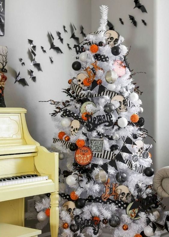 a white Halloween tree decorated with black and orange oranments, banners and garlands and skulls