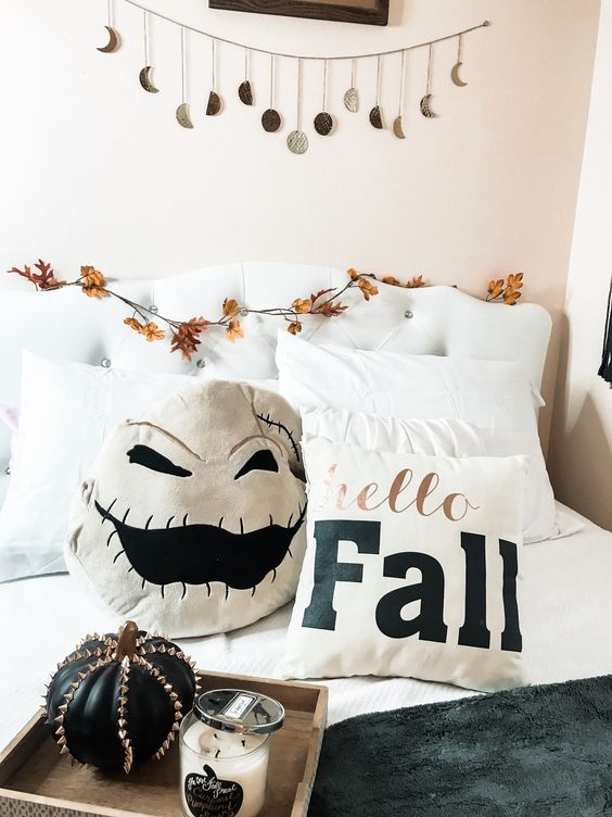 Add a scary pillow, a spiked pumpkin and a moon phase garland over the bed to make your bedroom more Halloween like