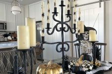 an elegant Halloween centerpiece of black, white and gold pumpkins, candlelabras with candles and cauldrons
