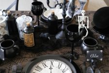 an elegant vintage Halloween centerpiece with black candles in a candelabra, black apothecary bottles and cups as cauldrons