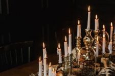 creepy and chic Halloween decor of skulls, bones, moss and candles in refined vintage candlesticks looks stylish and very elegant