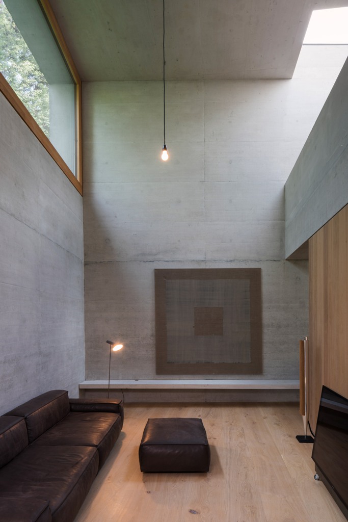 The living room is done with raw concrete, wood that softens the look and leather furniture