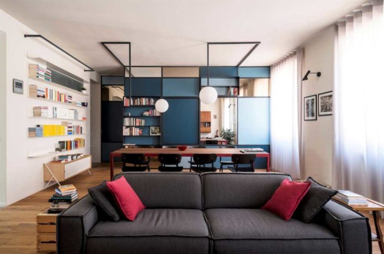 The main part of the dwelling is taken by a unique shelving unit in blue and navy, which divides the spaces and provides storage