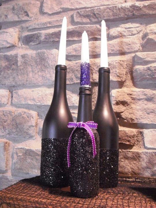 bottles painted matte black and blakc glitter with a purple bow and matching candles for Halloween candleholders