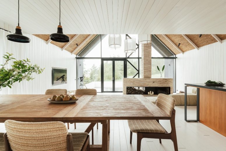 The interiors are all-neutral, with much wood and plywood, with a large fireplace, a cozy dining zone and lots of light coming through a glazed facade