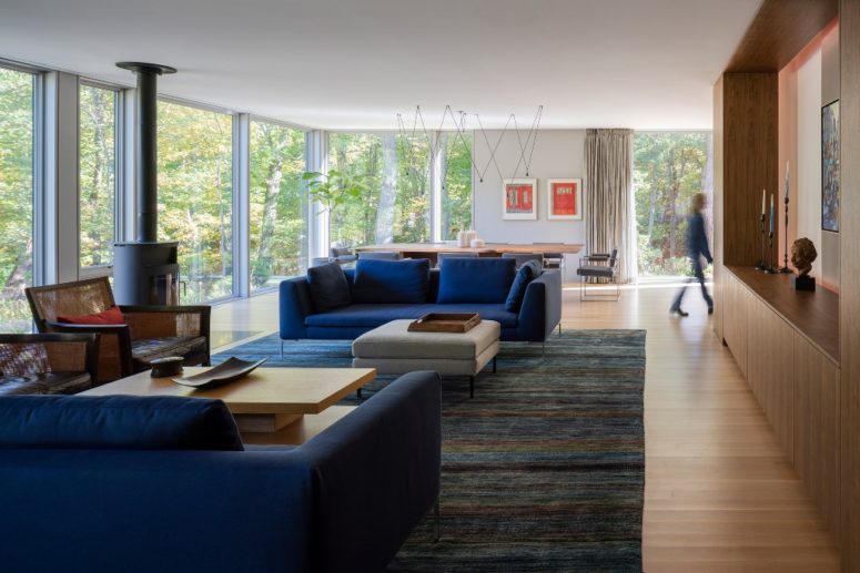 The living room is done with a heart, bold blue sofas and a glazed wall to unite with nature