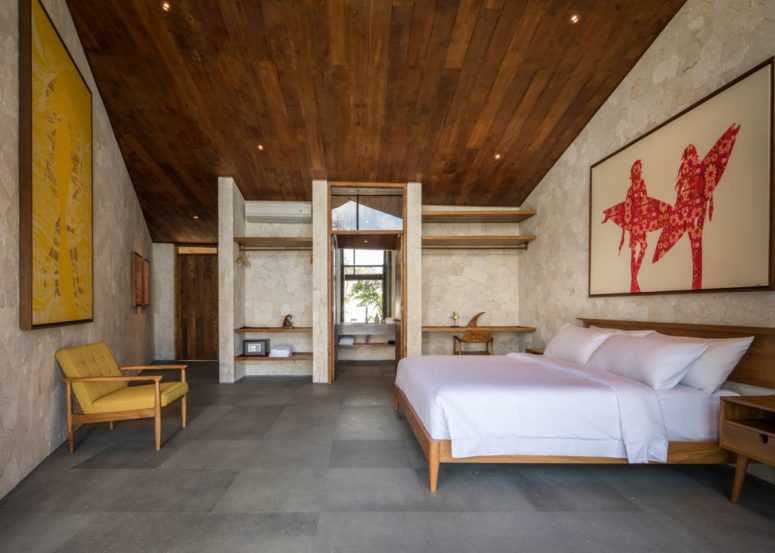 The bedroom is done in neutrals, a rich-colored wood ceiling, modenr furniure and open storage space
