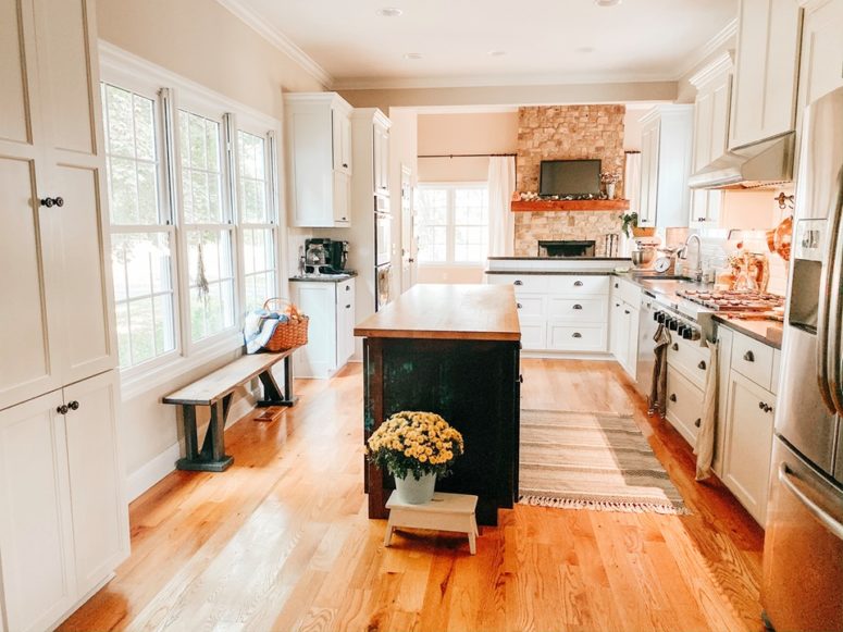 The kitchen is a light-filled space, with a brick backsplash, white cabinets and a black kitchen island