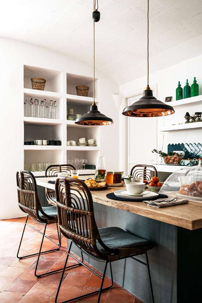 The kitchen is cozy and features built-in furniture, a kitchen island and rattan chairs and pendant lamps