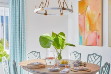 06 a white dining space infused with color using blue curtains and chairs and bright artworks on the wall