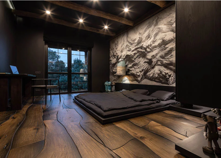 A moody bedroom features a unique textural wood floor, a statement wall and wooden beams on the ceiling