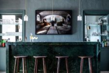 07 The bar space is done in dark greens, with an elegant marble counter, pendant bottle lamps and built-ins