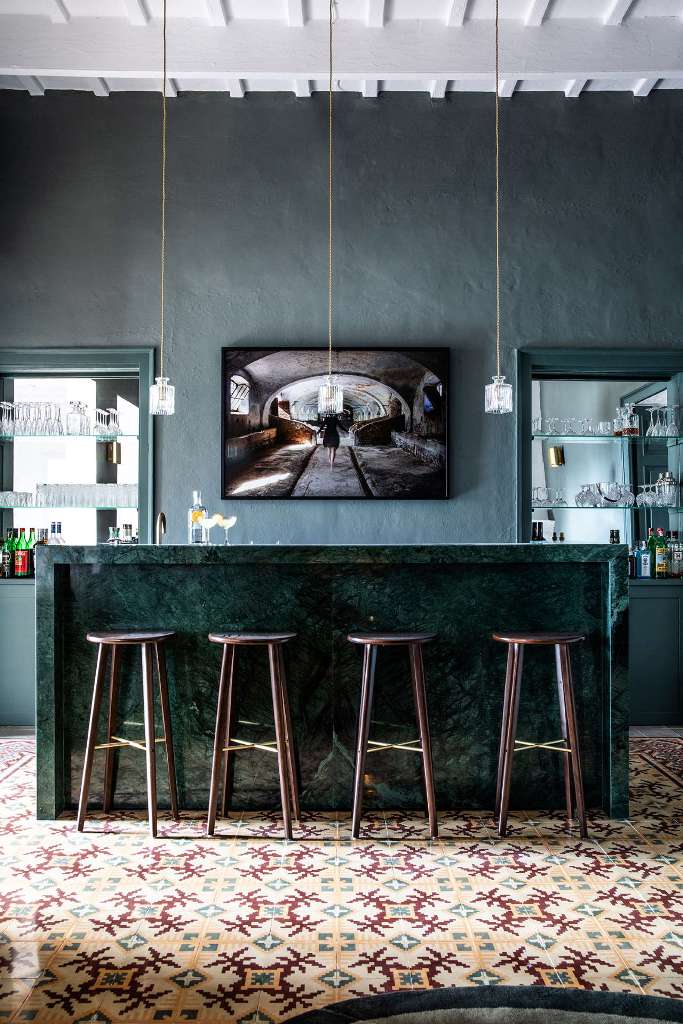 The bar space is done in dark greens, with an elegant marble counter, pendant bottle lamps and built ins