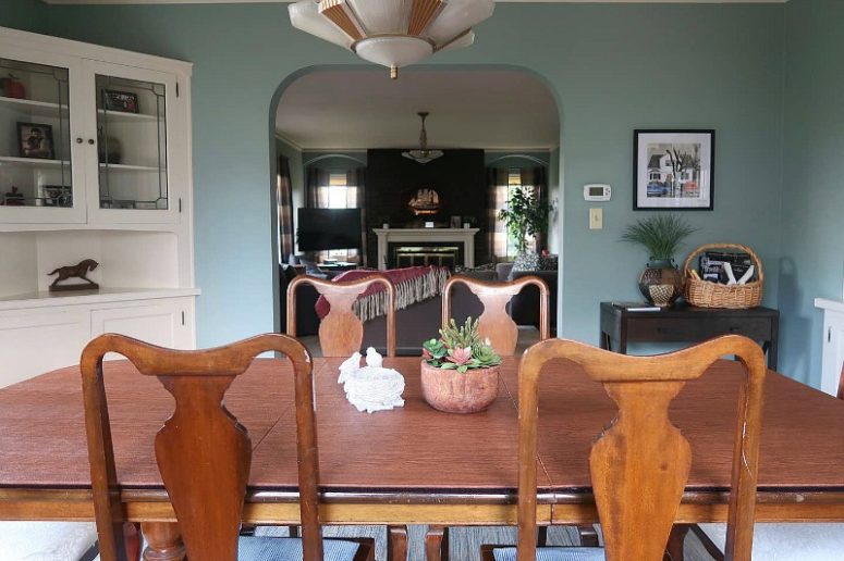 The dining room has blue walls, a vintage wooden furniture set, a corner buffet