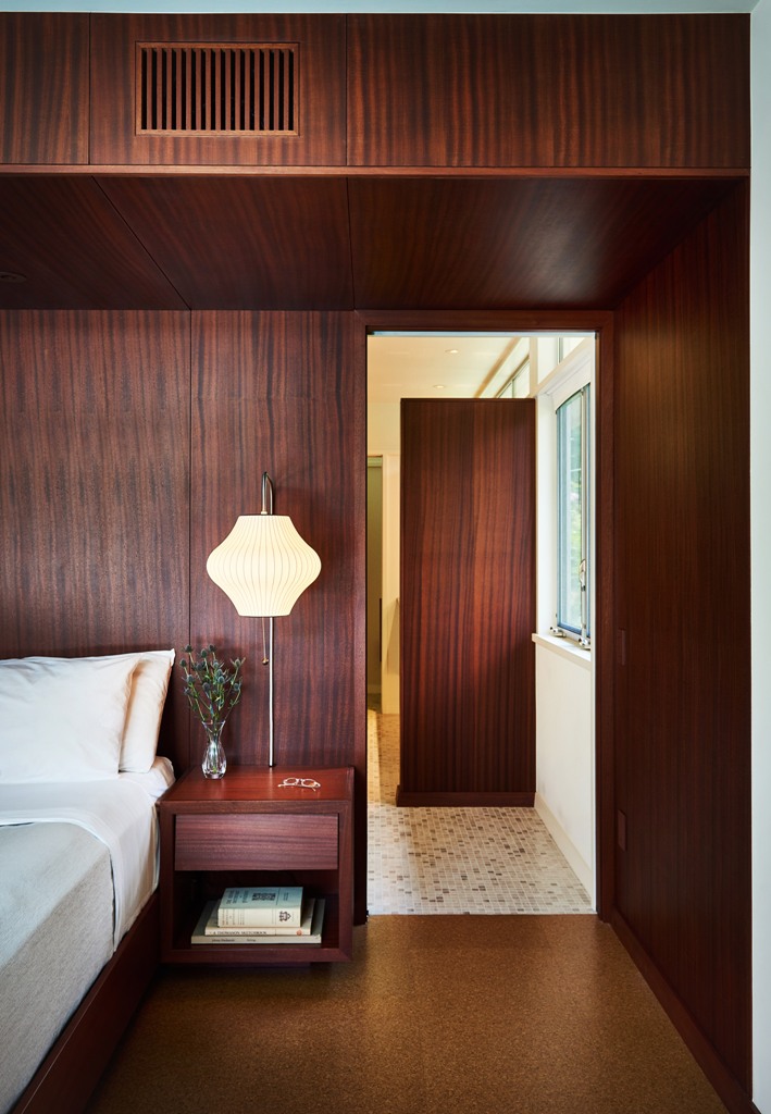 The bedroom is fully clad with mahogany, there are elegant lamps and a comfortable bed
