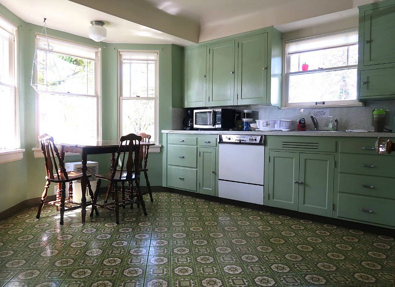The kitchen is done in green, with vintage cabinets that originate from 1930s