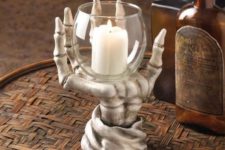 09 a skeleton hand holding a glass with a candle is a creative and bold idea for Halloween, which is always in trend