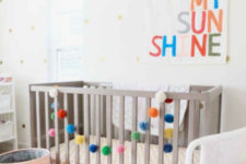 10 an all-neutral nursery with a colorful artwork, a bright pompom garland and a colorful striped chair
