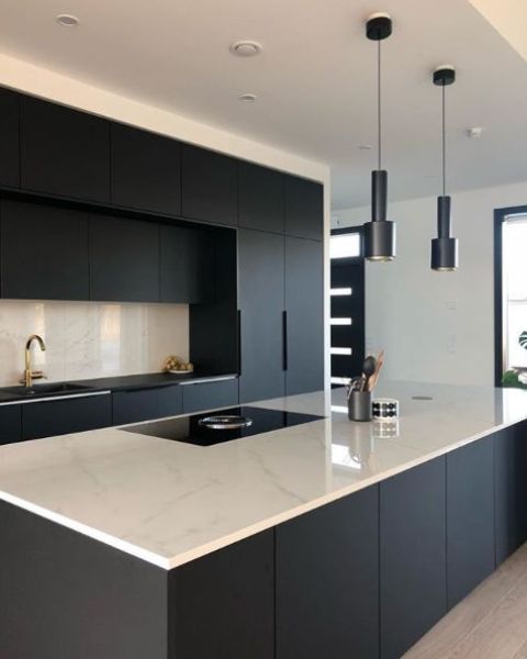 A stylish minimalist black and white kitchen with a white marble kitchen island countertop and a backsplash   just a bit of refreshing touches