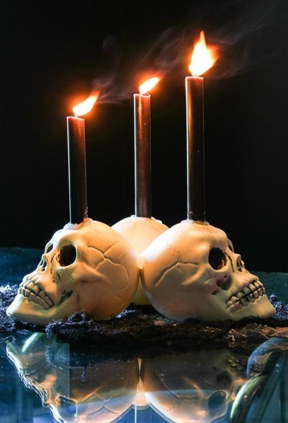 white skull candleholders with blakc candles are perfect for decorating your space for Halloween, simple and traditional