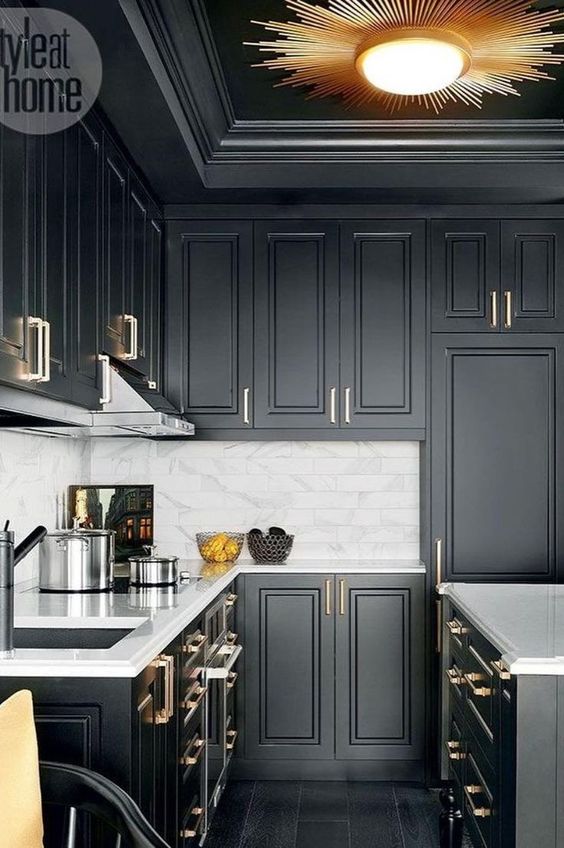 a black farmhouse kitchen refreshed wiith a white marble tile backsplash and metallic handles plus a sunburst lamp