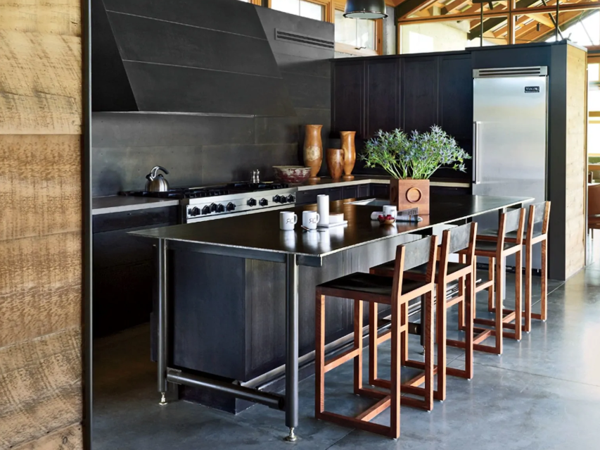A black kitchen spruced up with copper stools looks much more welcoming and soft than without them