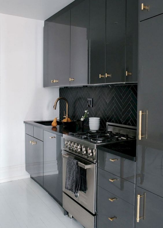 a modenr black kitchen refreshed with white surfaces and with gold handles all over that add a touch of glam