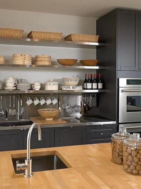 a black kitchen refreshed with a neutral backsplash, a wooden countertop and metal shelves, surfaces and faucets