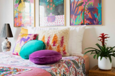 20 a colorful bedroom done in turquoise and purple, with colorful artworks over the bed, printed bedding and pillows