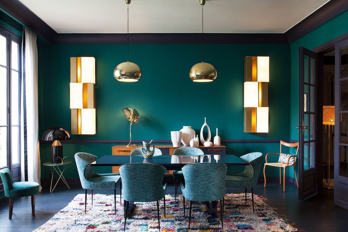 A bold monochromatic dining room done in blue and green, with metallic touches and with a colorful rug