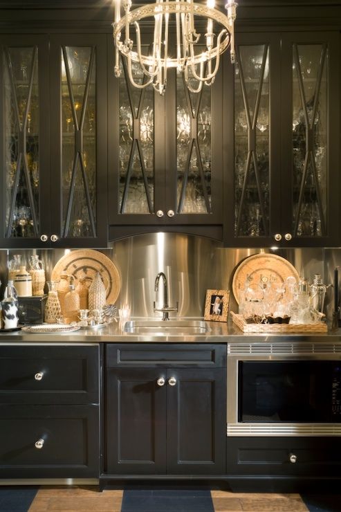 A vintage inspired black kitchen with a metallic backsplash, coutnertops and appliances looks very bold