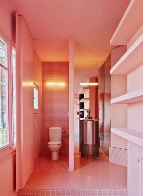 A whimsy bathroom done in salmon pink, with built in shelves and windows to floof the space with natural light
