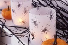 26 white candleholders with spiders drawn are a chic and simple DIY idea for Halloween decor