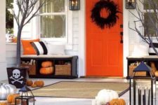 a colorful Halloween porch with a black feather wreath, orange and white pumpkins, candle lanterns and colorful and striped pillows