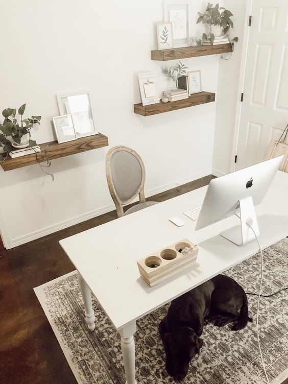 a cozy and simple home office with floating shelves, a simple white desk and a refined chair plus a printed rug