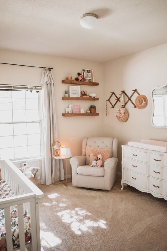 a cozy neutral nursery done with floating shelves, neutral curtains, vintage furniture, a cozy rug and some woven elements
