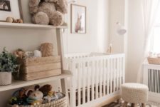 a neutral and cozy nursery with a rug, a knit stool, shelves, some touches of wood and some printed textiles
