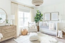 a neutral and fresh nursery with layered rugs, a woven lamp, a crib, a wooden dresser and a tree in a basket pot